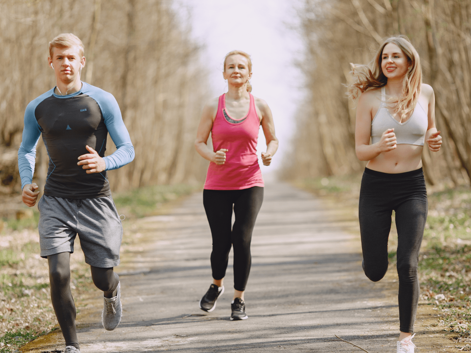 Жінка, дівчина та хлопець бігають в парку 